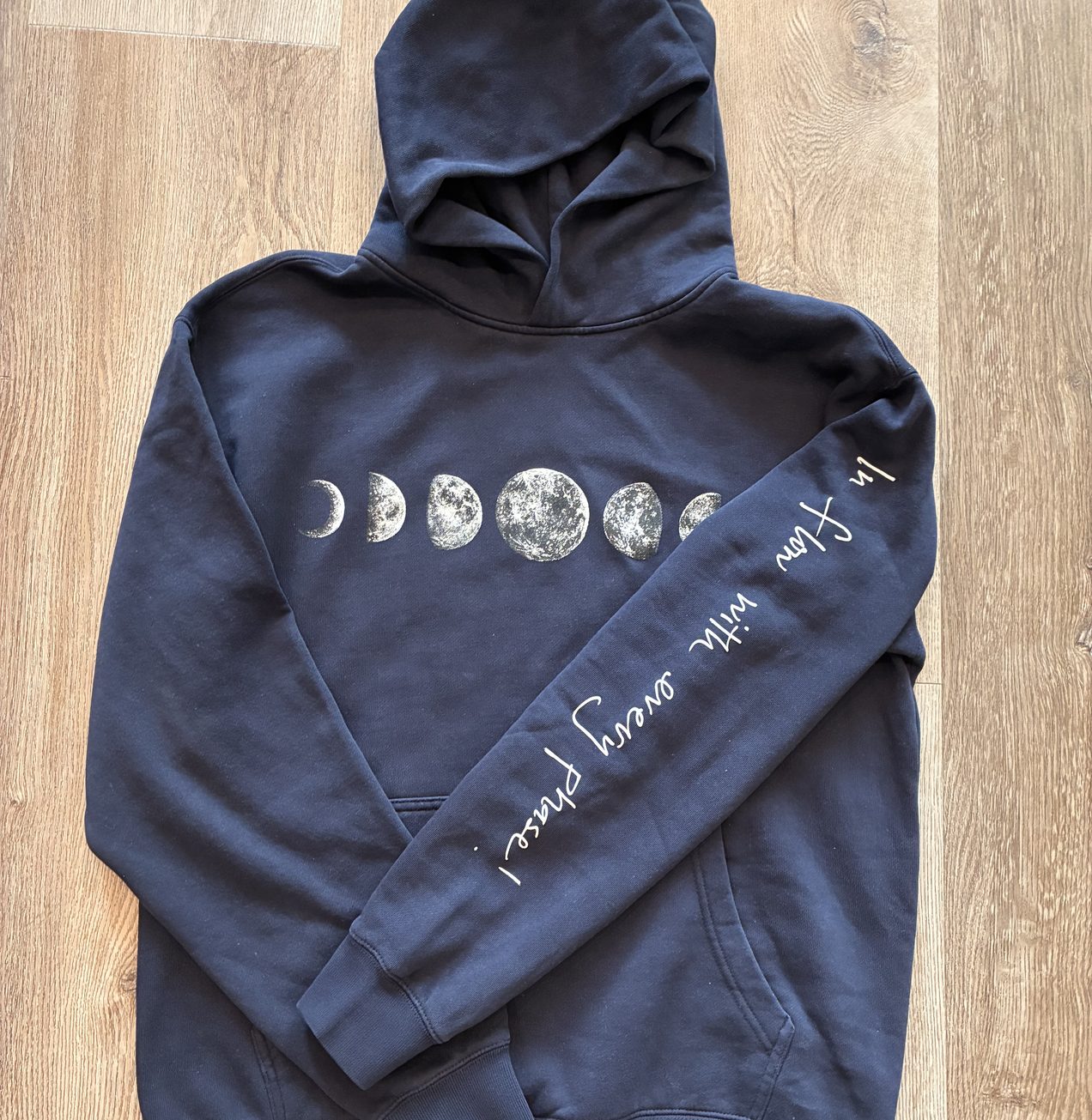 Moon Phase Hoodie flat-lay with the moon phases across the chest and the sleeve text
